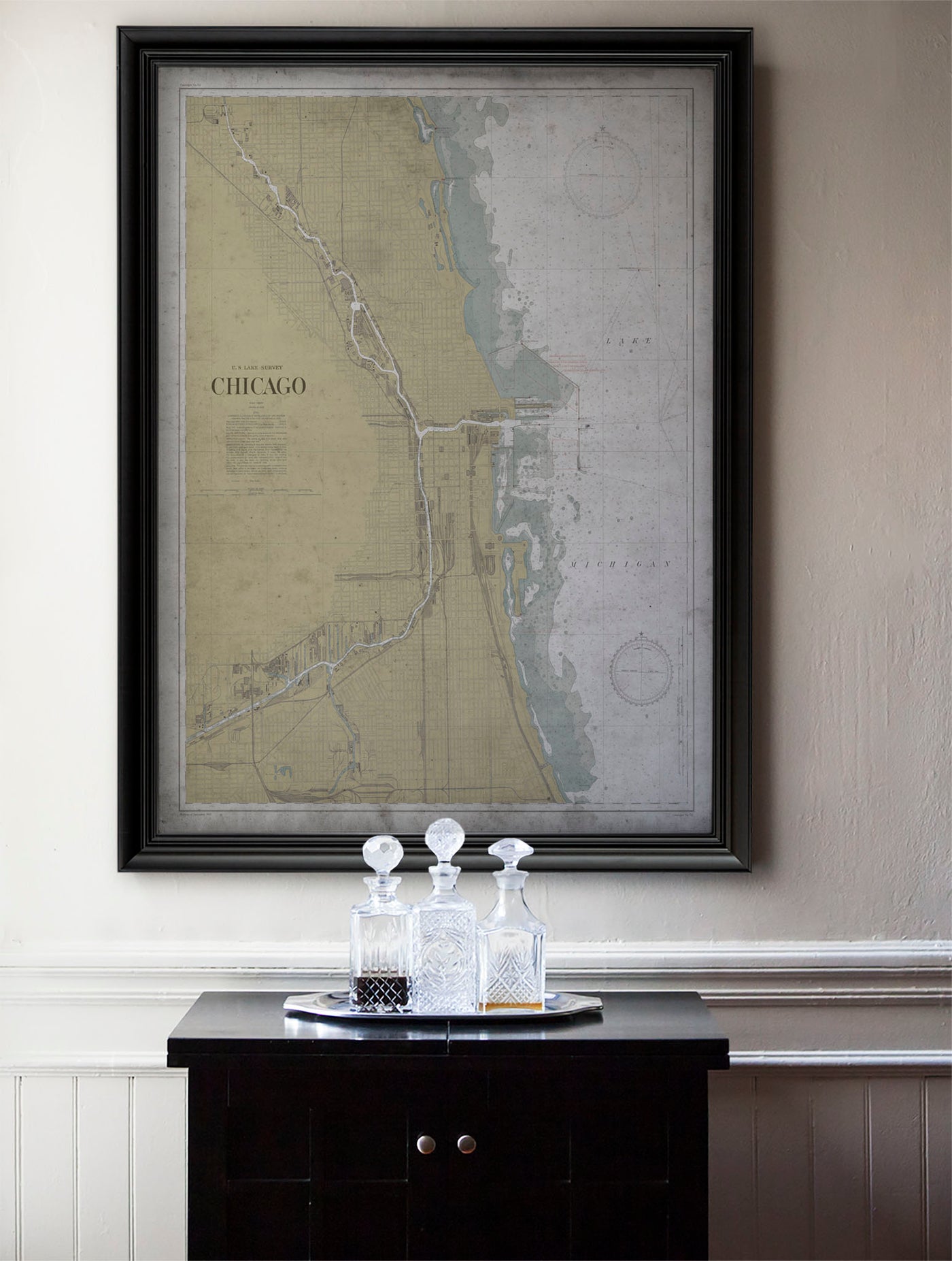 a framed map of Chicago, with a black tray holding three crystal goblets placed in front of it.