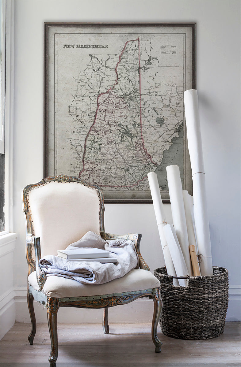 Vintage historic map of New Hampshire in room with white walls with vintage furniture and vintage decor.
