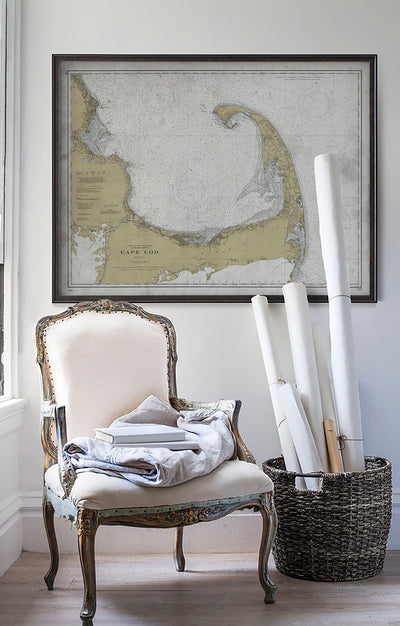 Vintage historic nautical chart of Cape Cod, Massachusetts in room with white walls with vintage furniture and vintage decor.