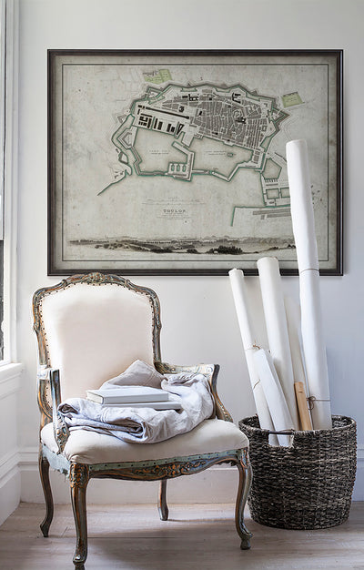 Vintage historic map of Toulon, France in room with white walls with vintage furniture and vintage decor.