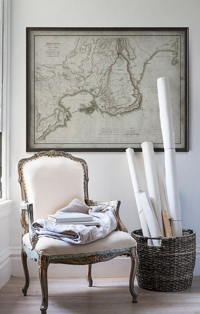 Vintage historic map of Syracuse, Italy in room with white walls with vintage furniture and vintage decor.