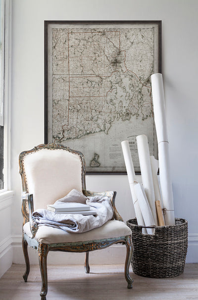 Vintage historic map of Rhode Island in room with white walls with vintage furniture and vintage decor.