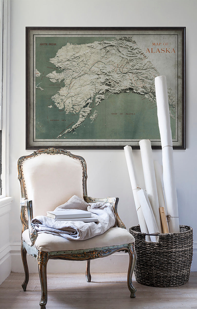 Vintage historic map of Alaska on white wall with vintage furniture and vintage decor.