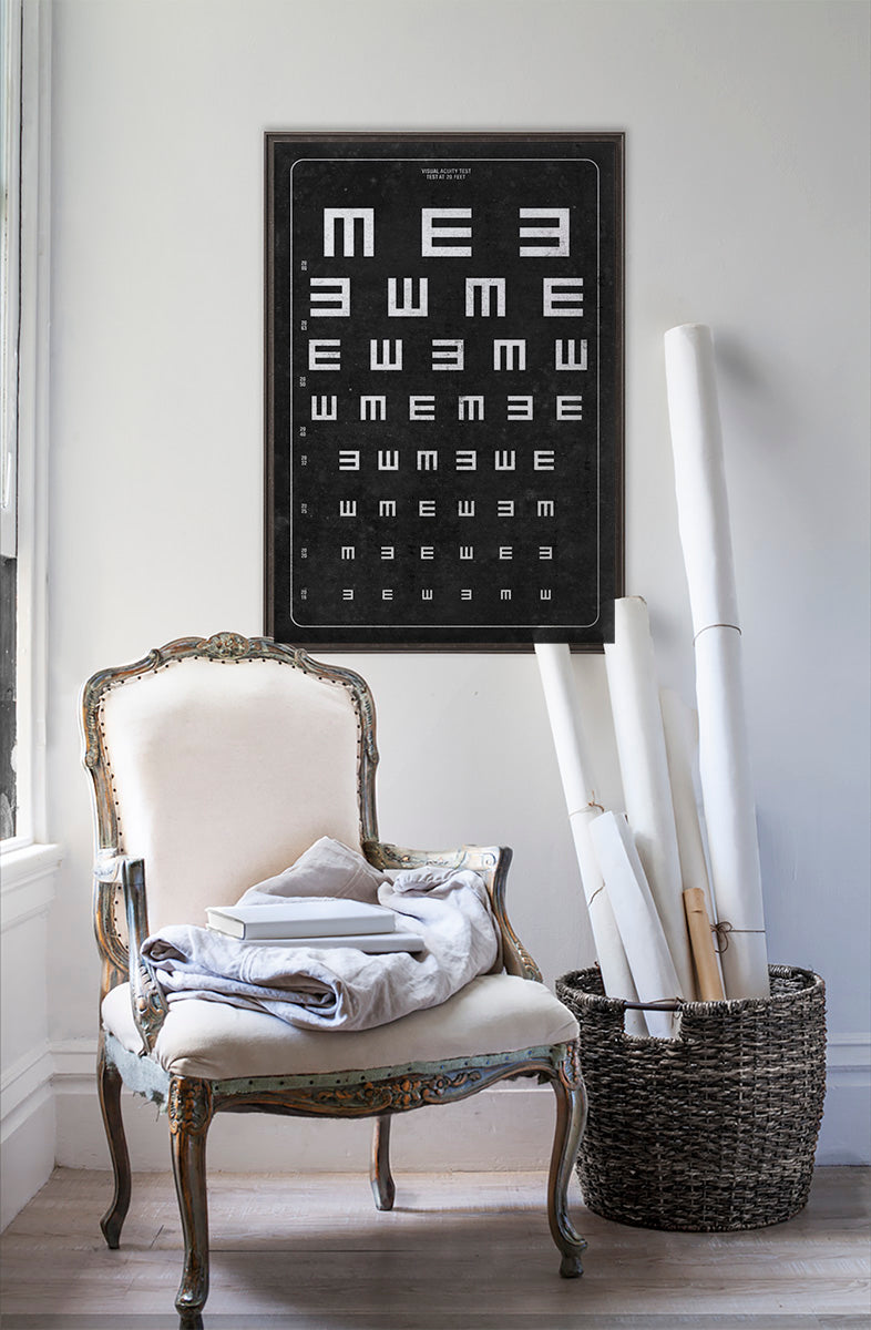vintage Tumbling E vision chart  in room with white walls with vintage furniture and vintage decor.