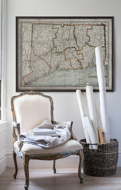Vintage historic map of Connecticut in room with white walls with vintage furniture and vintage decor.