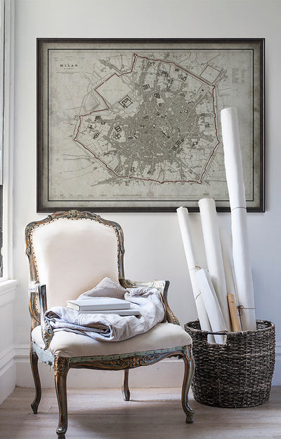 Vintage historic map of Milan in room with white walls with vintage furniture and vintage decor.